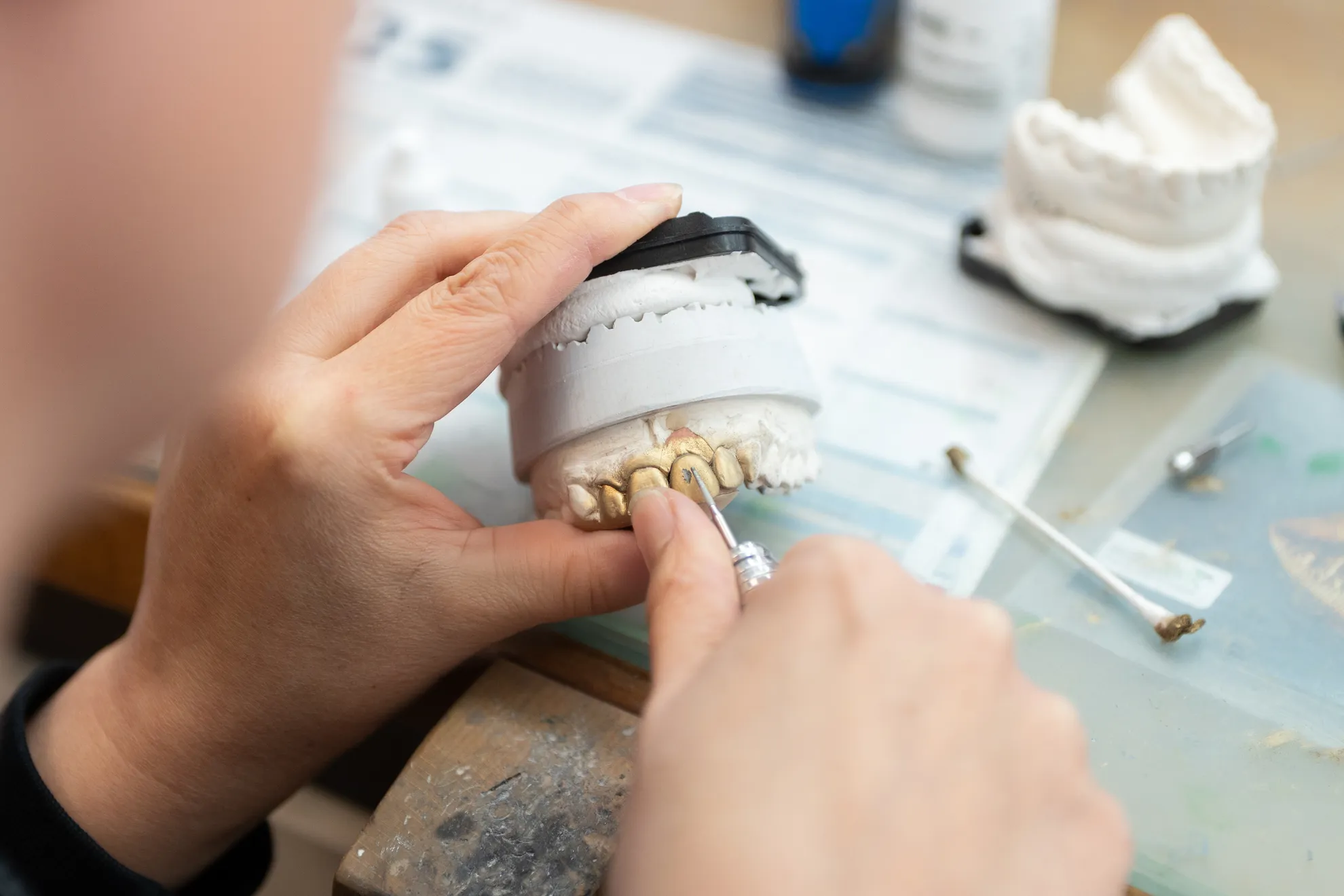 Eine Person bearbeitet ein Zahnmodell mit einem kleinen Werkzeug