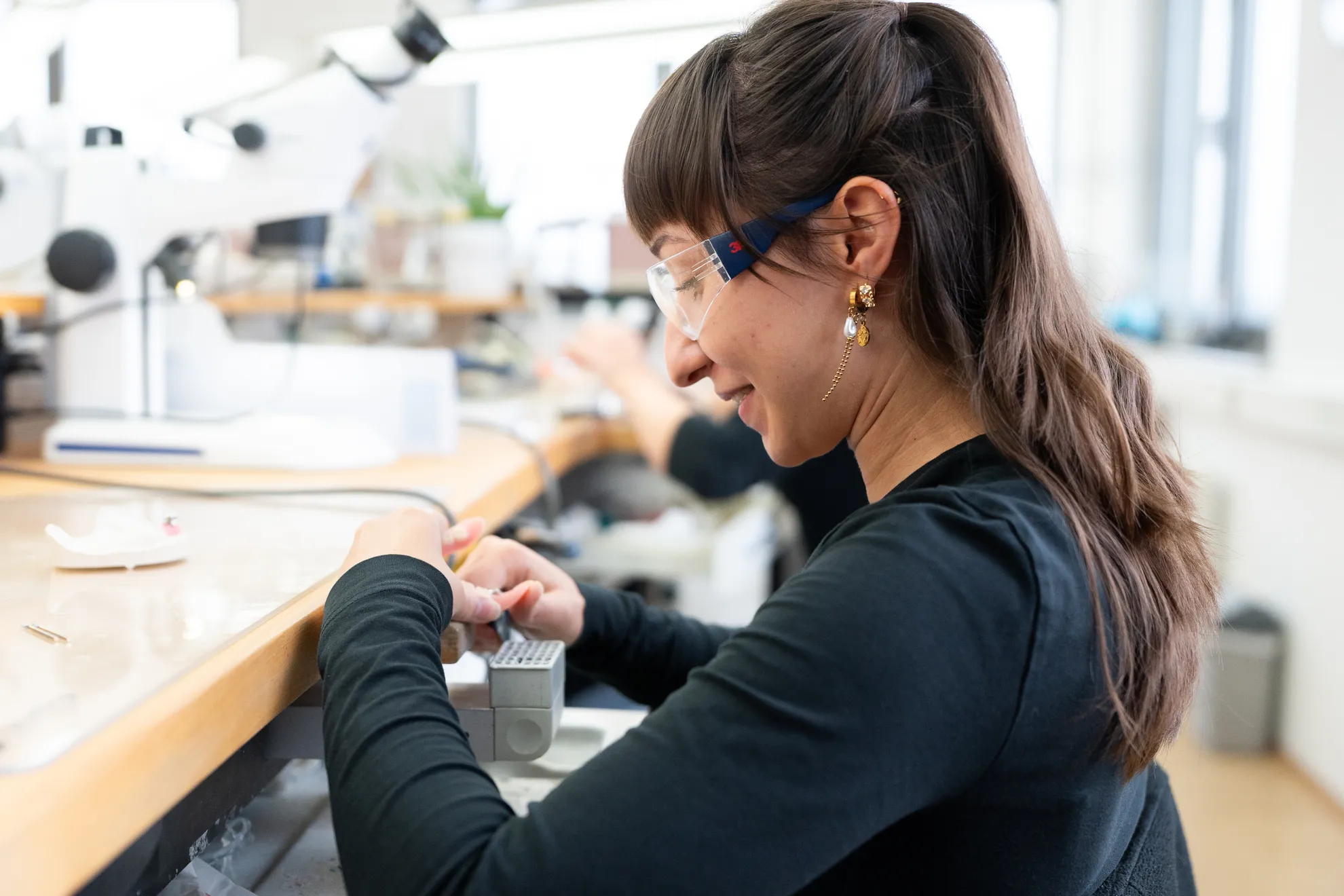 Eine Frau mit Schutzbrille arbeitet konzentriert an einem Gebissmodell